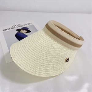 Detail of beige woven straw sun visor with striped ribbon and gold M metal buckle
