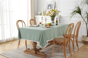 Close-up of light green cotton tablecloth featuring white pom-pom fringe detail
