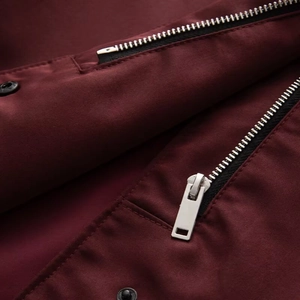 Macro detail of wine red jacket fabric and premium metal zipper closure on pocket