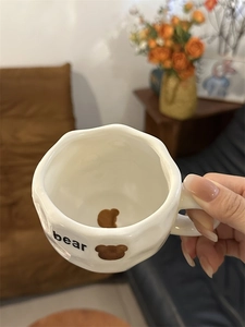 Detail of handmade ceramic coffee mug featuring hand-painted bear pattern and wavy rim design