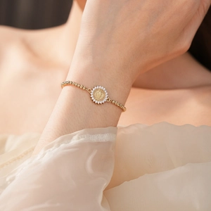 Gros plan d'un bracelet doré avec médaille de Saint-Benoît et zircons étincelants