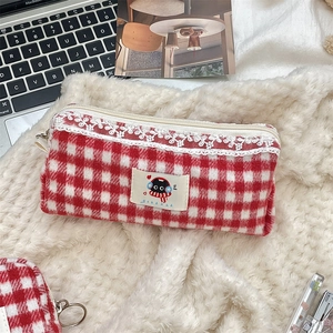 Close-up of a red and white checkered pouch with white lace trim and a cute cat patch