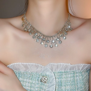 Detail view of shiny rhinestone flower fringe necklace set on model's neck for elegant look