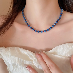Detail shot of the blue and red beaded necklace worn on neck for length reference