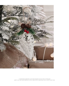 Close-up of pinecone ornament with red berries and burlap bow on a snowy Christmas tree