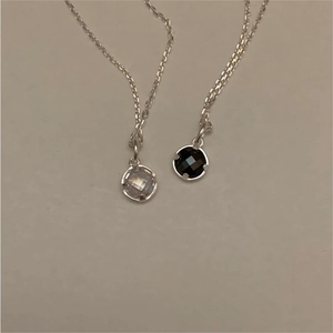 Detail view of two minimalist silver necklaces with black and clear multifaceted crystal charms