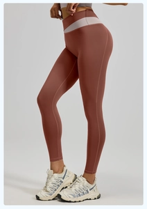 Detalle de leggings de yoga de cintura alta con tela rojo óxido y pretina de retales grises