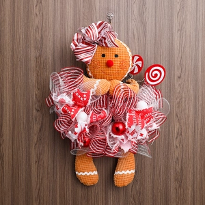 Detail of plush gingerbread man wreath decoration with candy cane and festive mesh bows