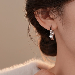Gros plan de créoles plaquées or 14K avec une perle blanche et une bille en métal