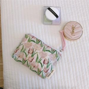 Detail view of floral tulip pouch with pink wristlet strap on white quilted background