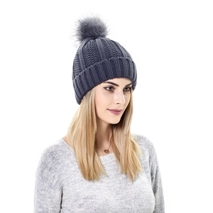 Detail of dark grey knit beanie featuring a soft faux fur pom and thick ribbed fold