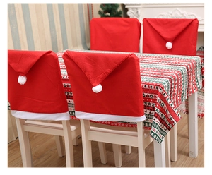 Close-up of festive red Santa hat chair covers and striped Christmas tablecloth set