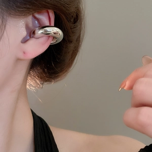 Détail d'une boucle d'oreille manchette torsadée en argent portée sur le cartilage