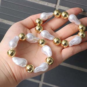 Close-up of baroque pearls and golden beads on an adjustable bracelet worn on wrist