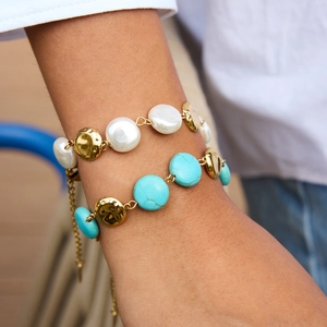 Vintage stainless steel bracelet set with white pearls and turquoise on a model's wrist