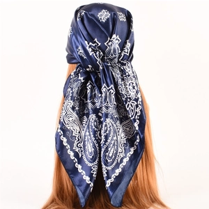 Macro shot of dark blue paisley silk scarf tied on head showing smooth glossy texture