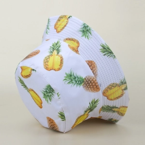 Close-up of a white bucket hat featuring a vibrant yellow and green pineapple print