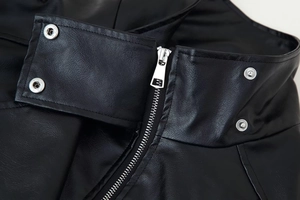 Macro view of black PU leather jacket with silver zipper and snap button detailing