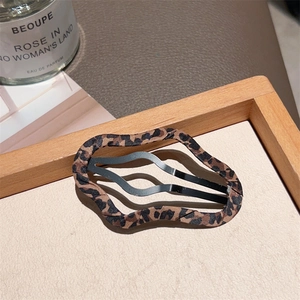 Close-up of wavy leopard print hair clip on a wooden tray with soft natural lighting