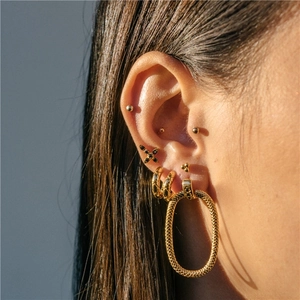 Close-up of model wearing a mix of gold textured hoops and polished star stud earrings