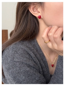 Close-up of elegant gold necklace and earrings set with red heart-shaped zircon stones