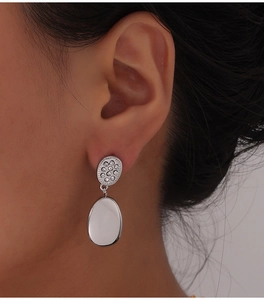 Close-up of silver oval drop earrings with shimmering zircon settings on a model