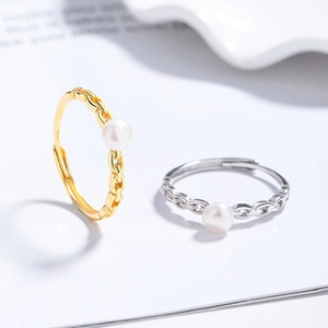Detail of adjustable pearl ring set with gold and silver woven chain bands for women