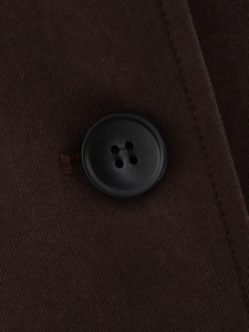 Macro detail of black resin four-hole button on dark brown twill fabric blazer