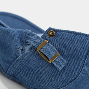 Detailed close-up of blue denim fabric with a vintage bronze metal adjustment buckle