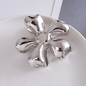 Close-up of a silver flower metal hair claw clip placed on a white ceramic plate
