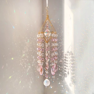 Pink and clear K9 crystal suncatcher with golden frame creating rainbow light patterns
