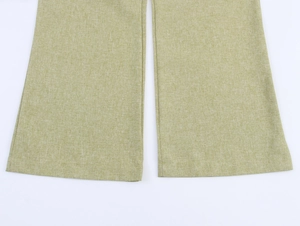 Macro detail of light green linen fabric texture and hem stitching on wide-leg trousers