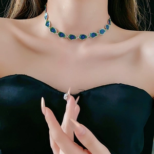 Peacock feather pendant necklace in blue and green enamel worn by a model