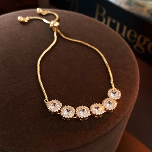 Close-up of gold-plated bracelet with six cubic zirconia stones and adjustable bead clasp