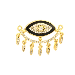 Macro detail of gold-plated evil eye pendant with black enamel and zircon tassels
