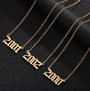 Vue détaillée de colliers en acier doré avec pendentifs année 2000-2002 en police gothique