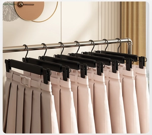 Detail showing non-slip black clips on frosted hangers holding several pleated skirts