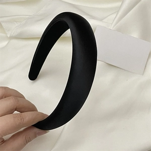 Close-up of a thick black satin padded headband featuring a smooth glossy texture finish