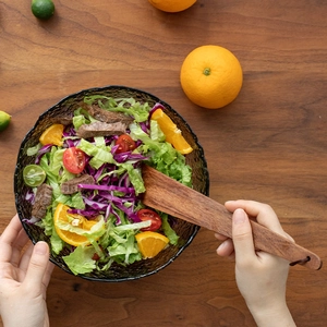 Spatule en bois d'acacia et bol en verre martelé avec salade de bœuf sur table en bois