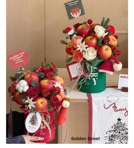 Close-up of Christmas flower box with fresh red apples, roses and festive pine branches
