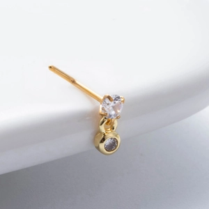 Macro de piercing de nez doré orné de deux zircons clairs sur un fond blanc épuré