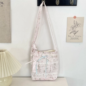 Floral tulle shoulder bag with lace details and ribbon bows hanging on a white wall