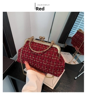Detail of red tweed handbag with gold metal frame and elegant chain strap on a black table
