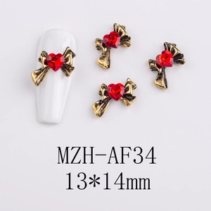 Detail of vintage gold alloy heart nail charms with red crystal and bow design