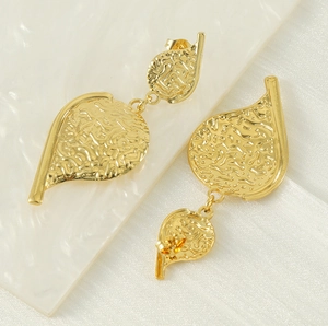 Detail of gold-plated titanium leaf earrings featuring vintage hammered textures on white