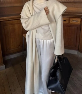 Detail view of cream double-sided camel wool coat with stylish waist tie and white trousers