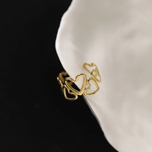 Bague large ouverte en forme de cœur dorée sur une assiette blanche et fond noir