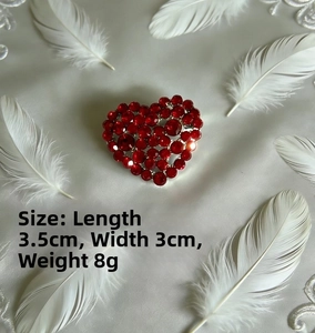 Macro shot of 3.5x3cm silver heart brooch with deep red crystals on silk