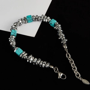 Detail of titanium steel bracelet with turquoise beads and lobster clasp on dual-tone background