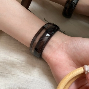 Detail showing high-shine dark brown resin bangle with vintage amber texture and wide band
